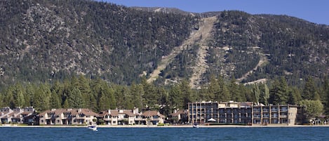 A coastal hotel with multiple buildings, a beach, and a mountainous backdrop.