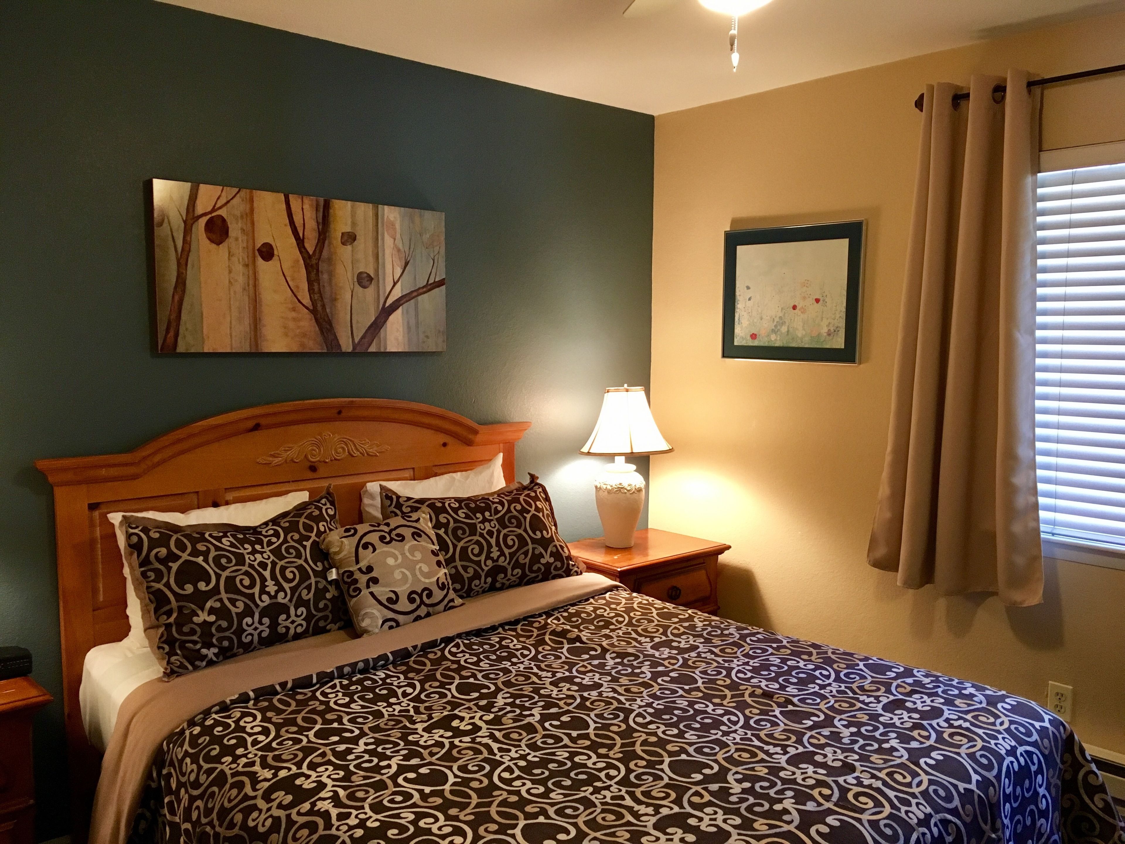 A bedroom with a bed, a nightstand, a lamp, and two wall art pieces.