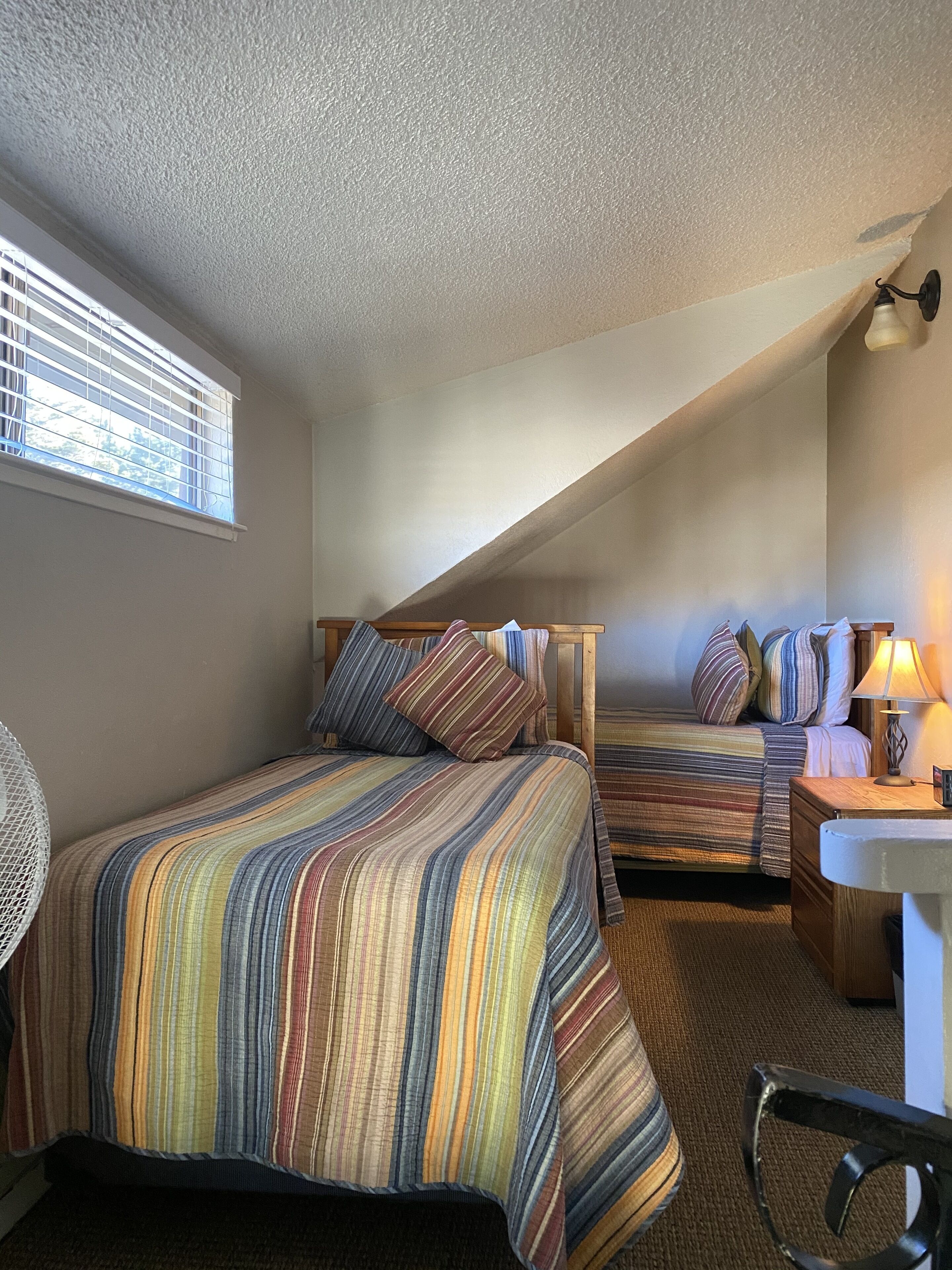 A bedroom with two beds, a small desk, and a chair.