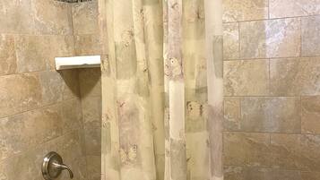 A bathroom with a bathtub, shower, and a curtain with a butterfly pattern.