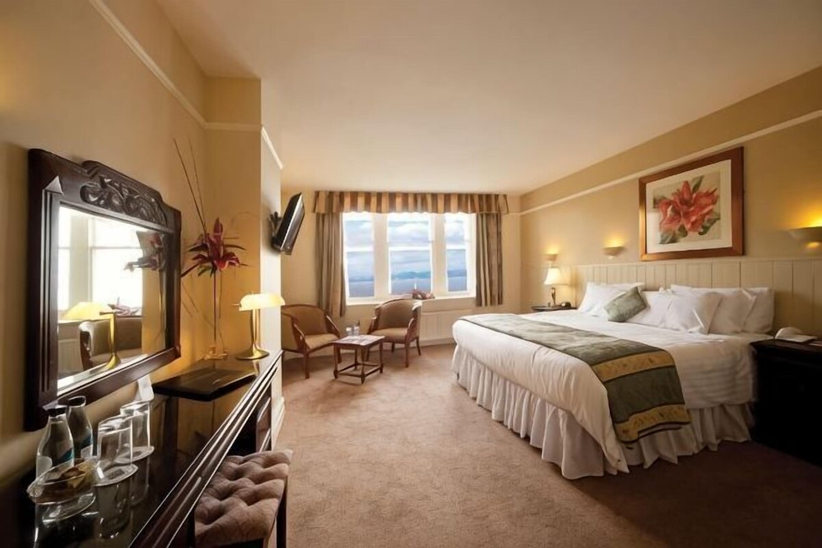 Une chambre d’hôtel avec un lit, un bureau, une chaise, une télévision et une fenêtre.