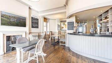 Ein Restaurant mit Barbereich, Holzboden, weißen Möbeln und einem Kamin.