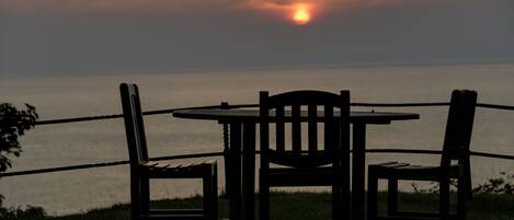 A table and two chairs by a lakeside at sunset.