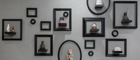 A wall with various framed artworks and sculptures, including a bust, a small American flag, and a model of a building.