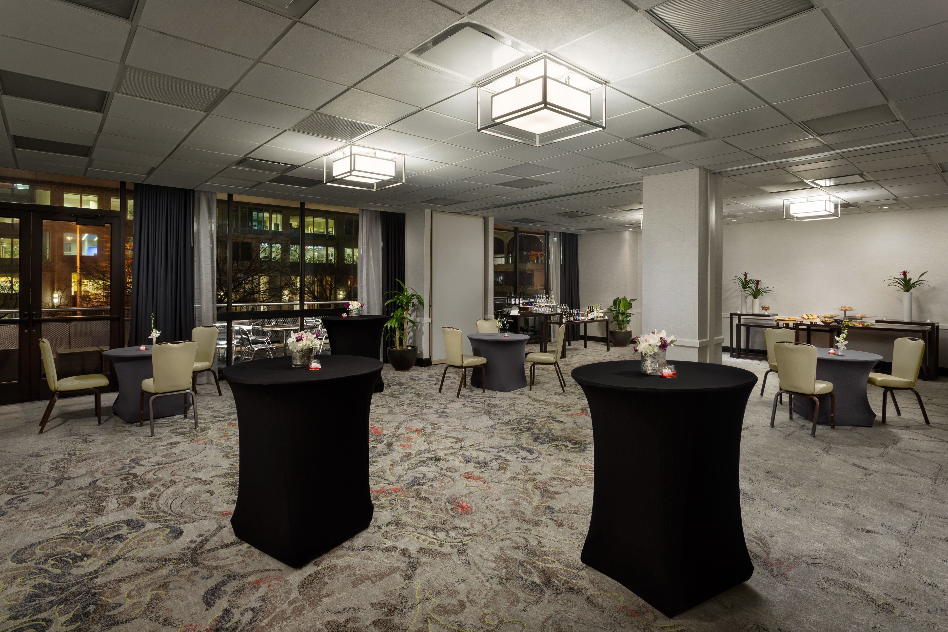 A conference room with round tables, chairs, and a bar area.
