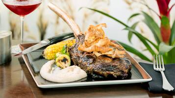 A plate with grilled meat, corn on the cob, and a side of mashed potatoes.