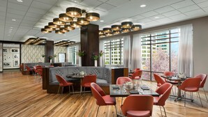 Un comedor amplio con suelo de madera, sillas rojas y una zona central de estar con un banco acolchado.