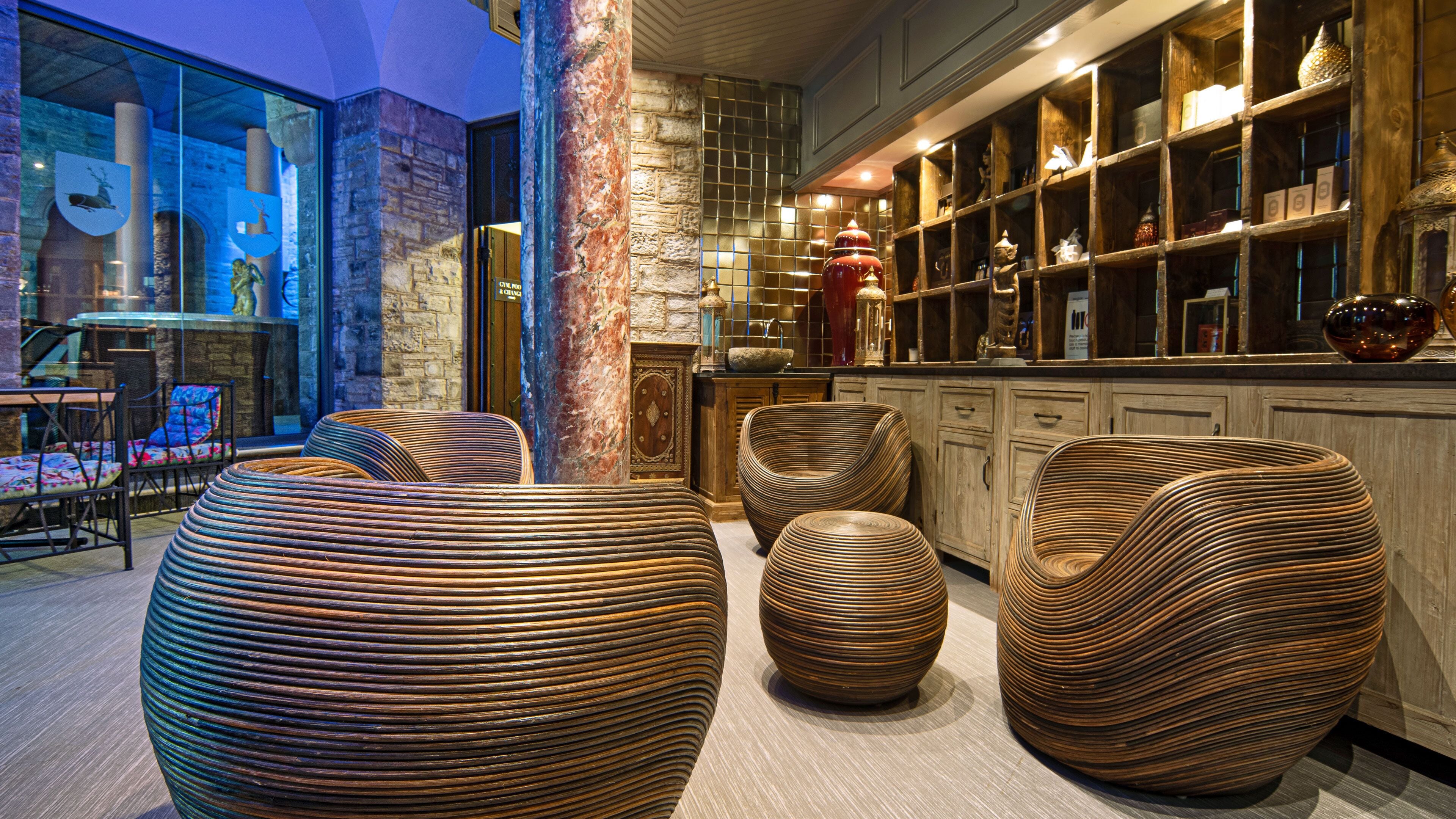 A modern interior with large, ribbed seating, a stone pillar, and a bar area with shelves of decorative items.