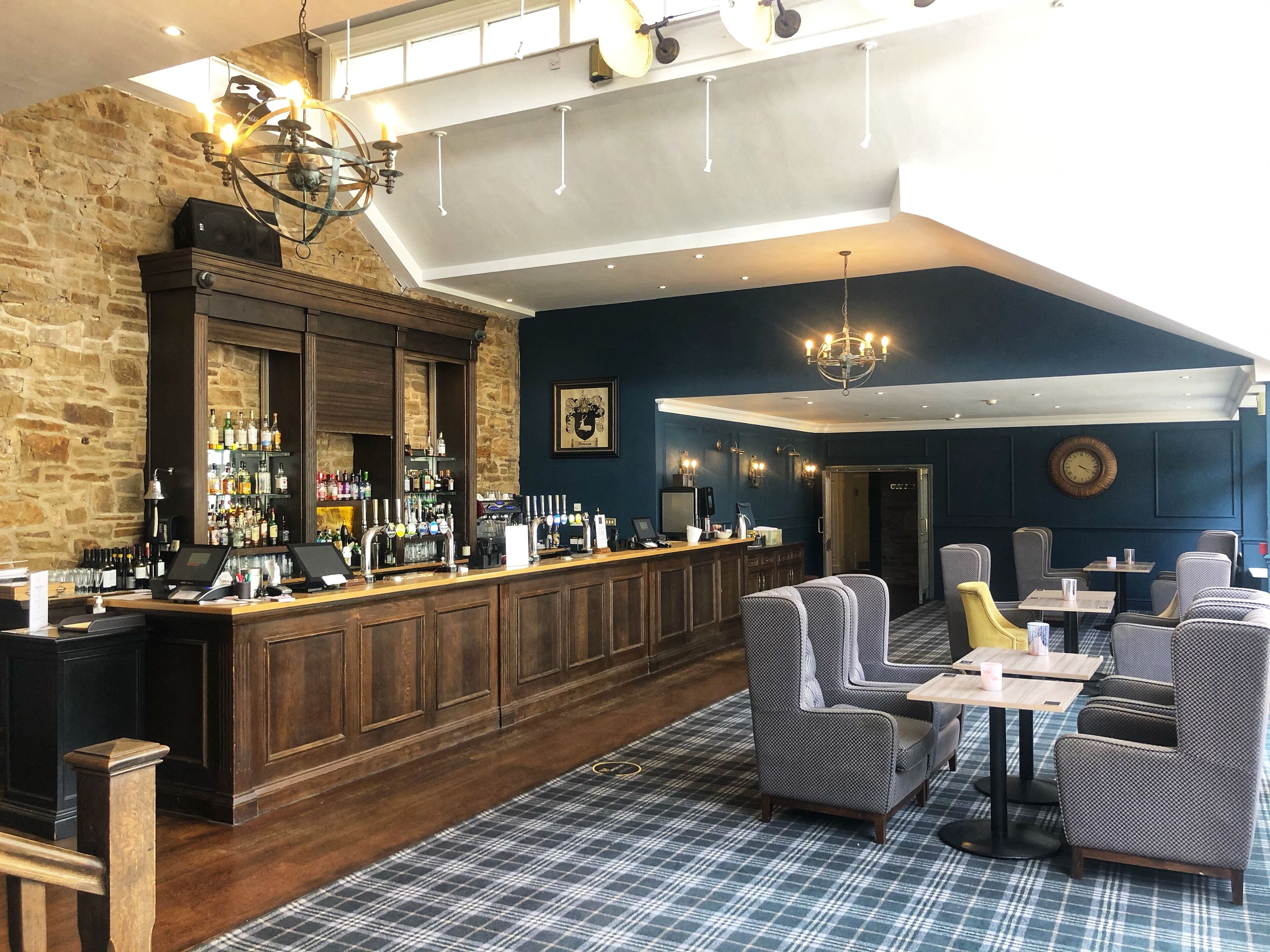 A bar area with a wooden counter, bar stools, and a patterned carpet.