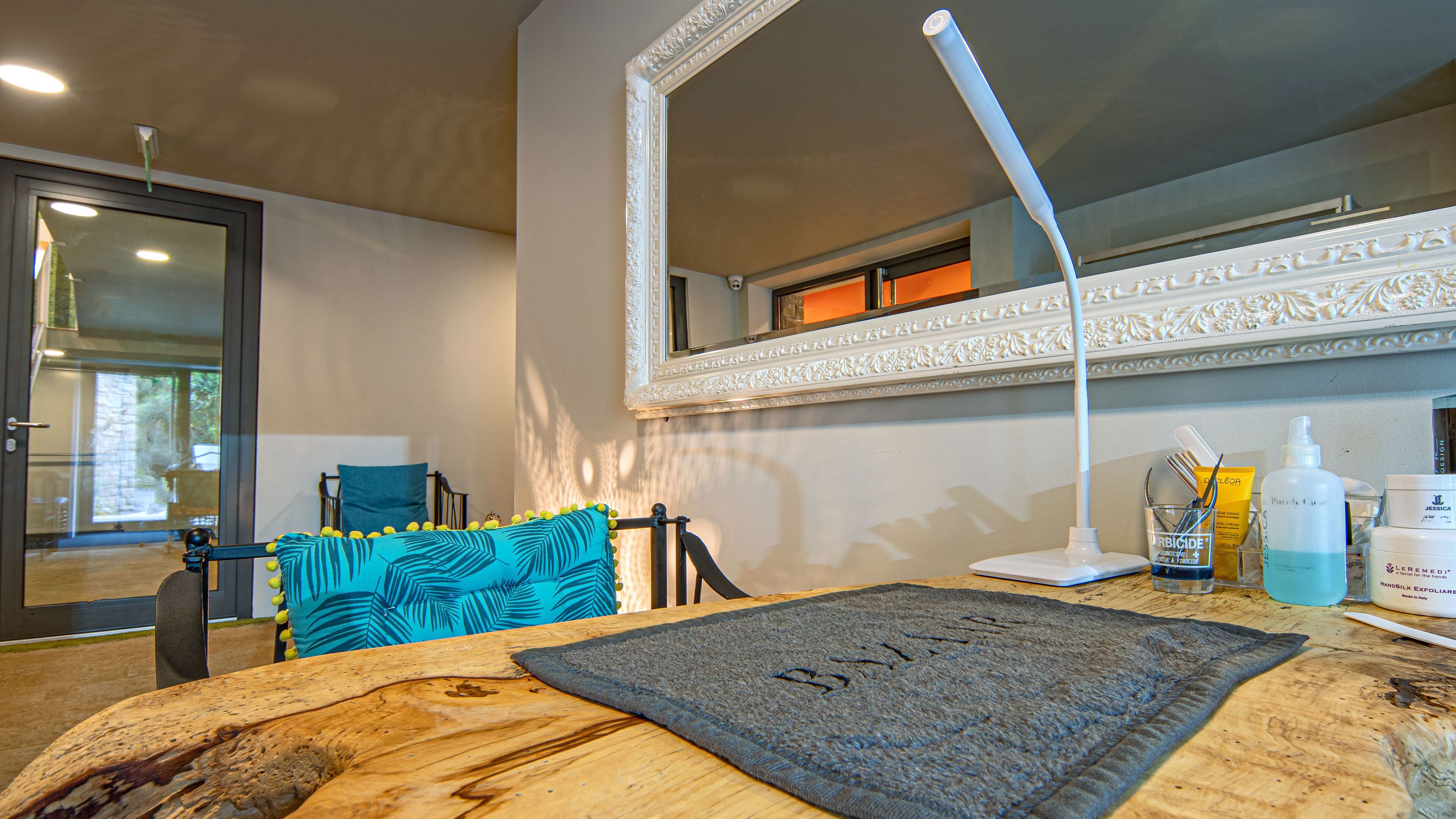 A bathroom with a wooden vanity, a large mirror, and toiletries on the counter.