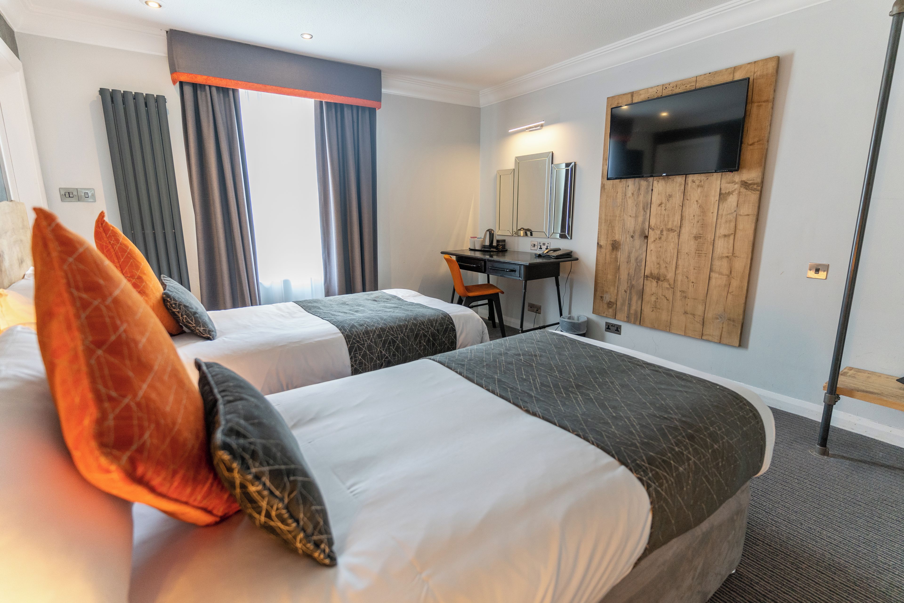 Een hotelkamer met twee bedden, een bureau, een stoel, een televisie en een spiegel.