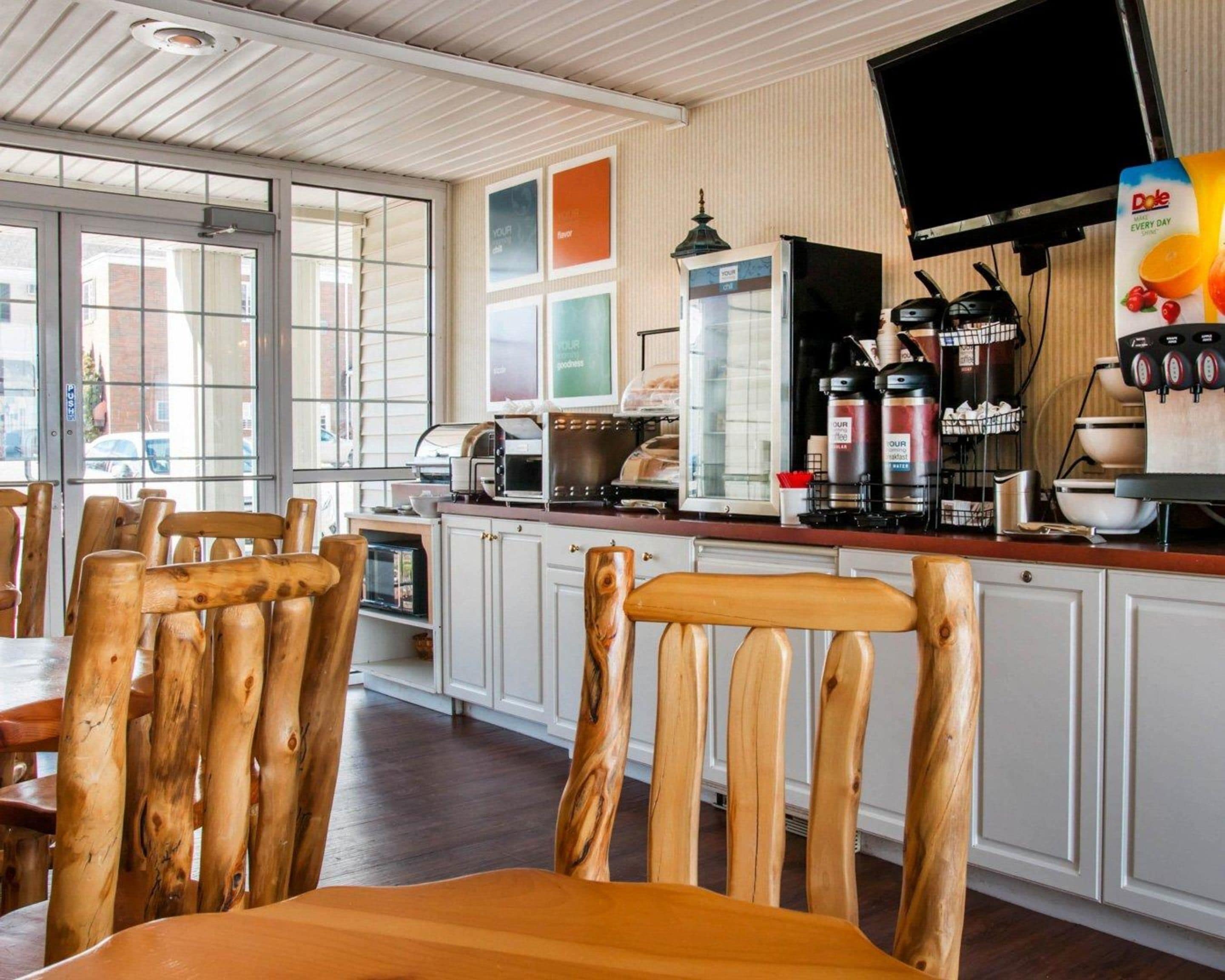 A restaurant interior with wooden chairs, a counter with coffee machines, and a large window.