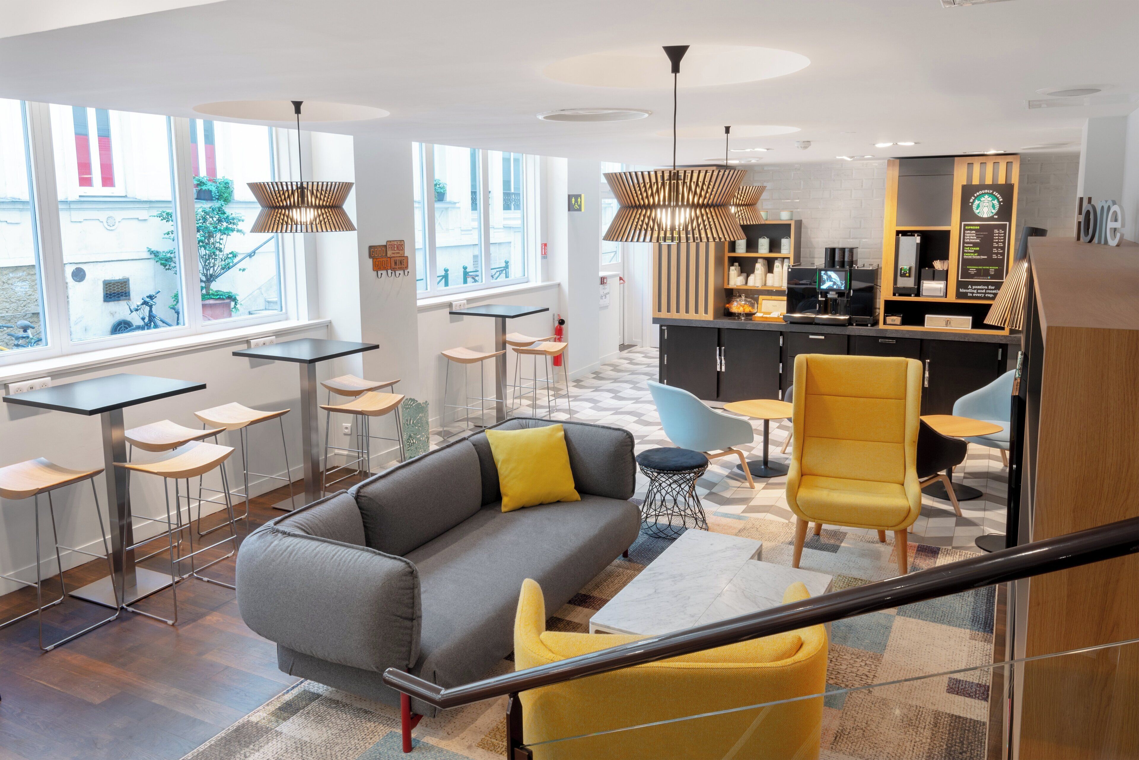 A modern interior with a sofa, yellow chairs, a bar area, and large windows.
