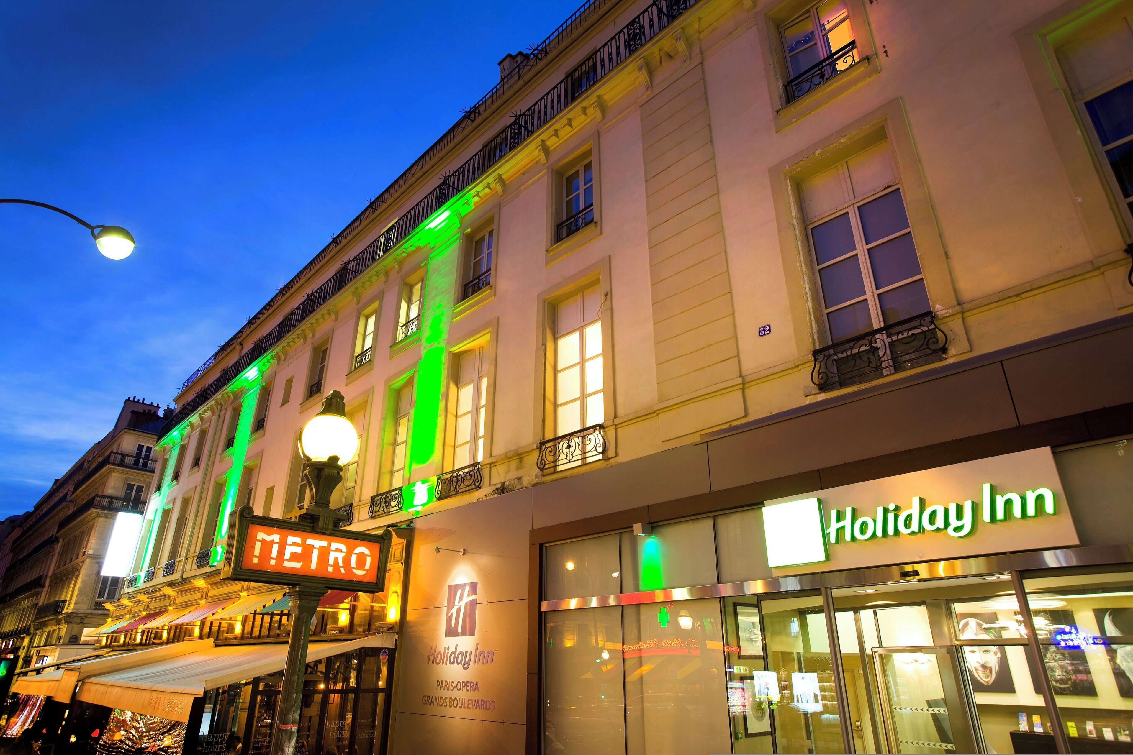 A building with a 'Holiday Inn' sign, a 'METRO' sign, and a street lamp.