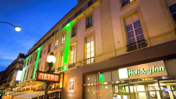 A building with a 'Holiday Inn' sign, a 'METRO' sign, and a street lamp.