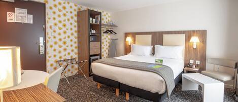 A hotel room with a bed, bedside tables, a desk, a chair, a wardrobe, and a shower area.
