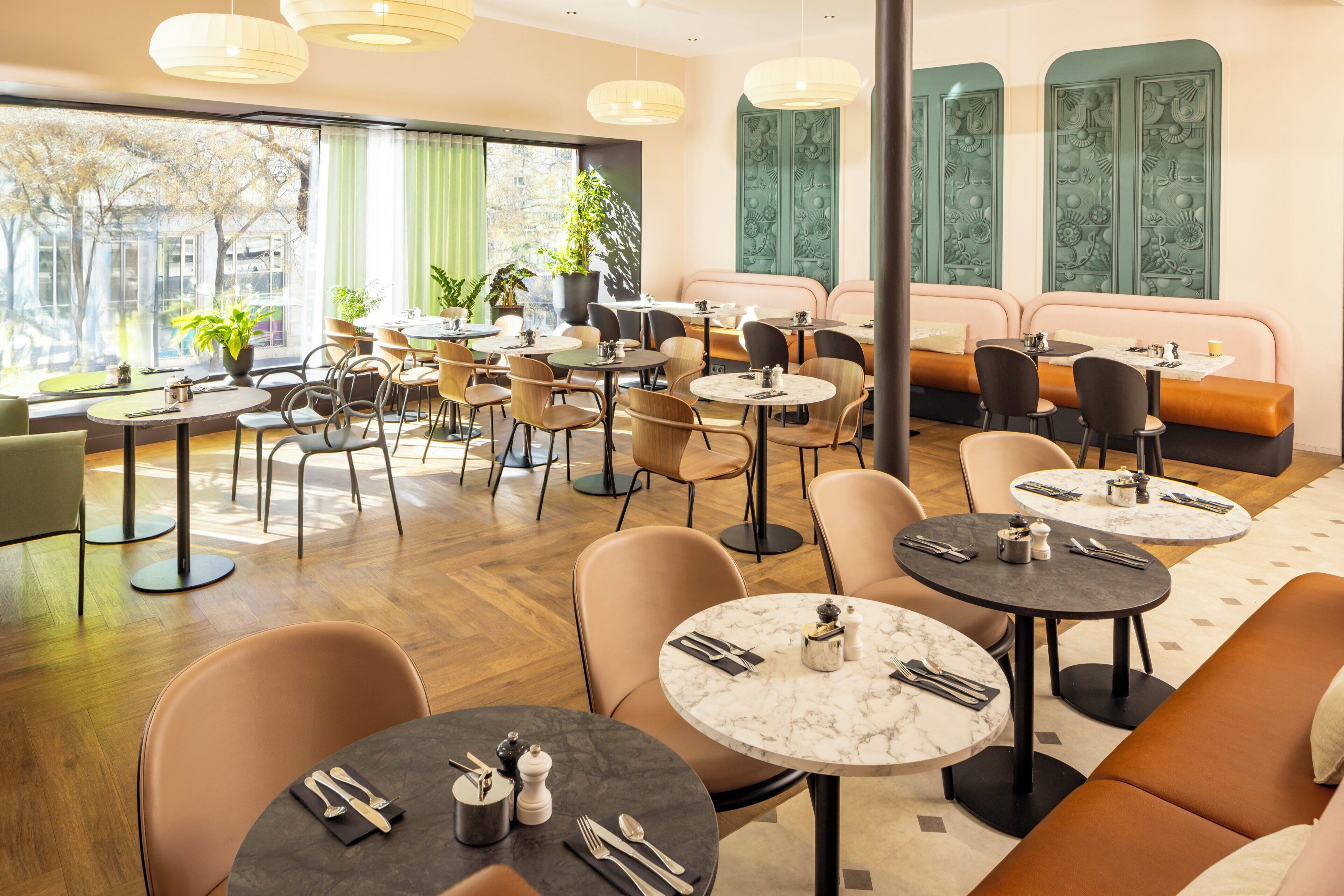 Un restaurante moderno con mesas redondas, asientos acolchados y paneles decorativos en las paredes.