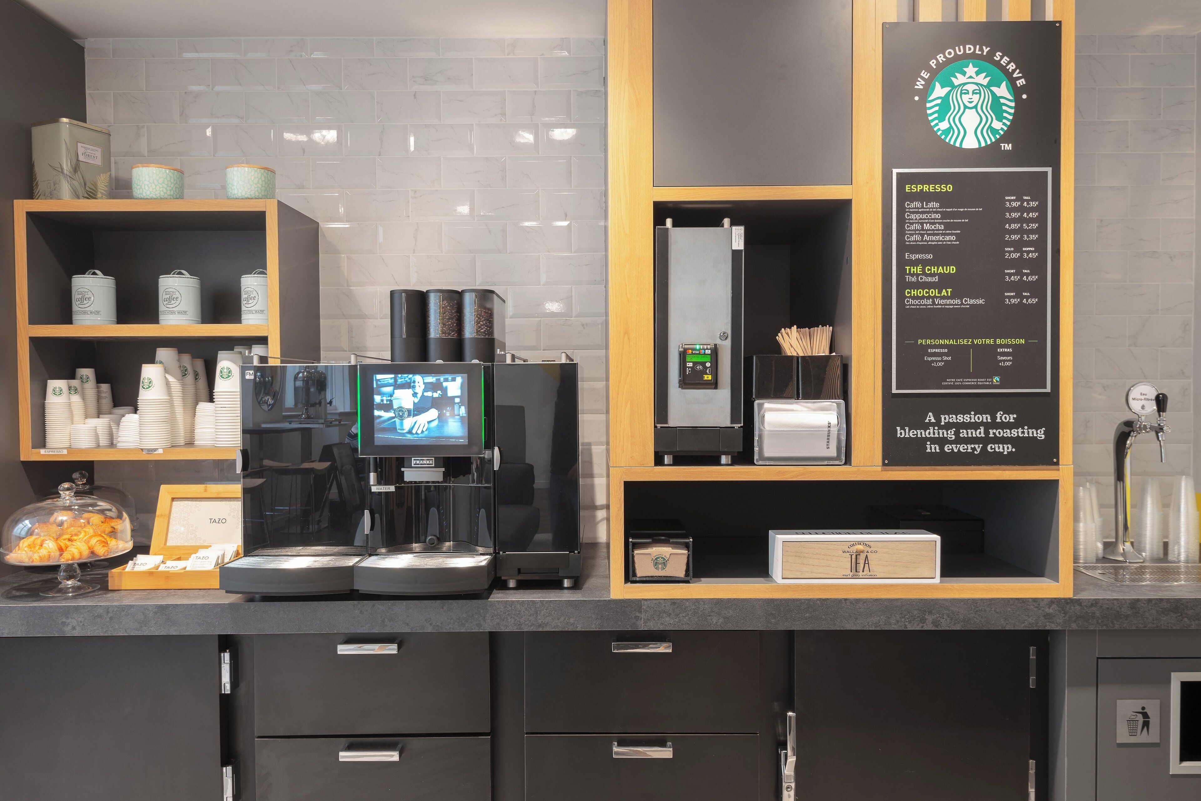 L'intérieur d'un café, avec une machine à café, un tableau affichant le menu et des étagères remplies de contenants à café.