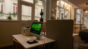 Un espacio de oficina moderno con un escritorio, computadora y vistas a la calle a través de grandes ventanales.