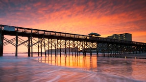 A pier extending into the water with a sunset in the background. - Tides Folly Beach, Charleston's Oceanfront Hotel (Folly Beach)