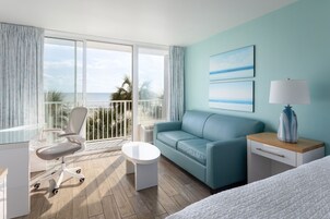 Quarto de hotel com varanda, sofá, escrivaninha e cama.