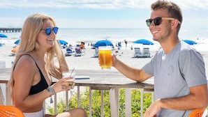 Two people sitting at a wooden deck with a view of the beach and ocean. - Tides Folly Beach, Charleston's Oceanfront Hotel (Folly Beach)