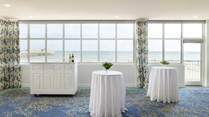 A room with large windows, a white reception desk, and two round tables with white tablecloths. - Tides Folly Beach, Charleston's Oceanfront Hotel (Folly Beach)