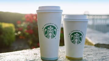 Two Starbucks cups with lids on a textured surface.