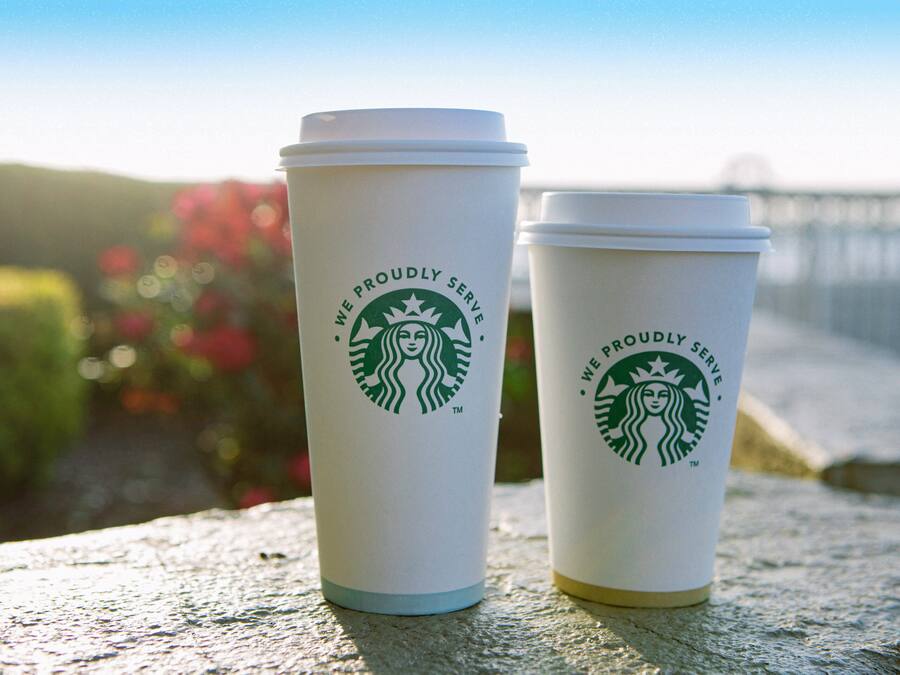 Two Starbucks cups with lids on a textured surface.