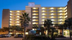 A multi-story hotel with a prominent 'TIDES' sign, multiple balconies, and a parking area with several cars. - Tides Folly Beach, Charleston's Oceanfront Hotel (Folly Beach)