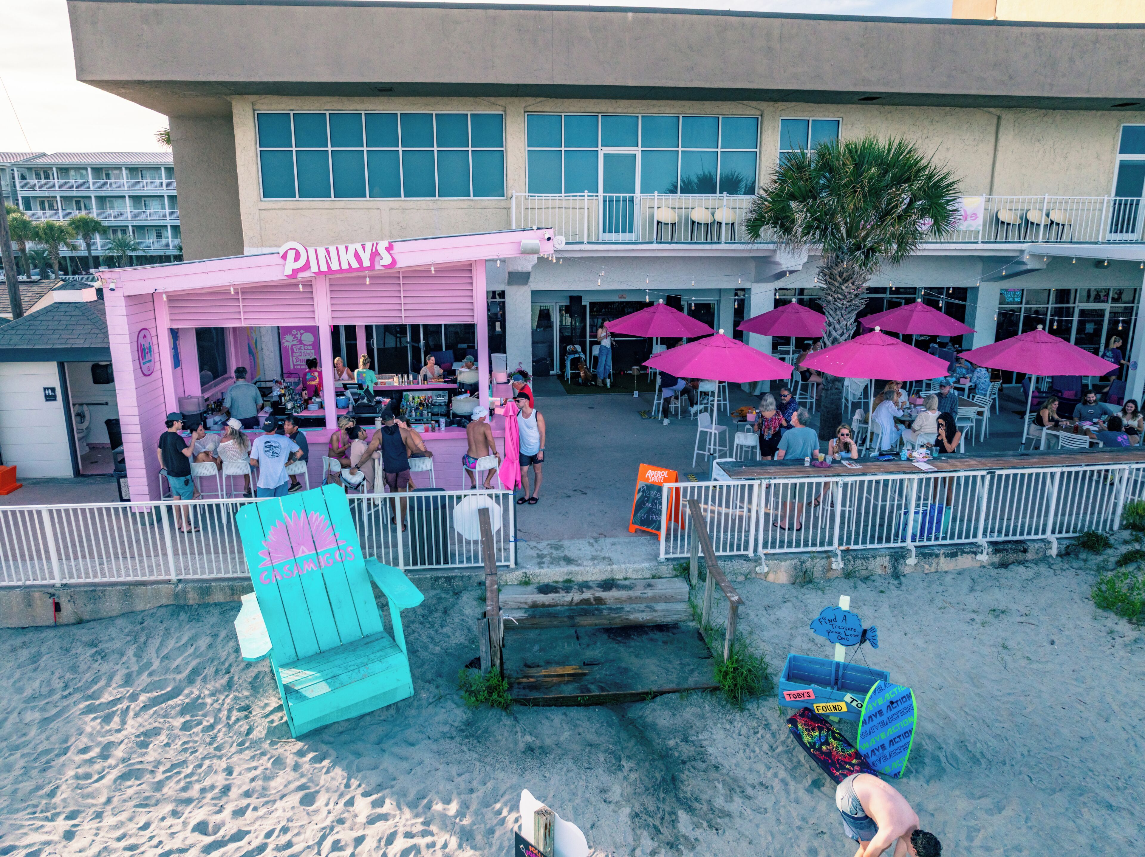 Un restaurante frente a la playa con mesas al aire libre y sombrillas.