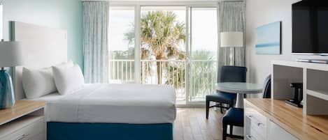 A hotel room with two beds, a desk with a chair, a TV, and a balcony with a view of palm trees.