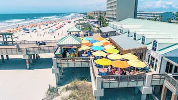 A beachside hotel with a pier, outdoor seating, and a view of the beach.