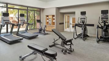 A gym with treadmills, a bench press, and dumbbells.