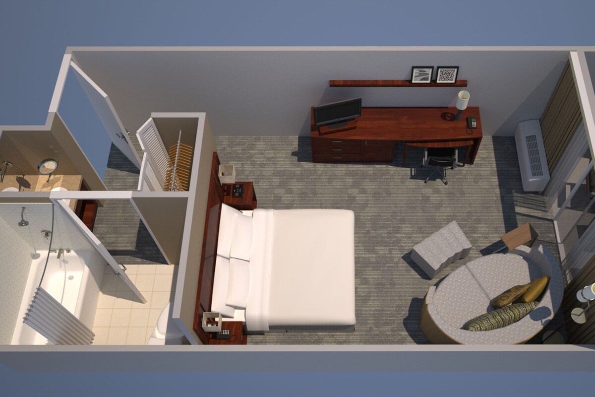 Een 3D-model van een hotelkamer met een bed, bureau, stoel en een klein zithoekje met kussens.