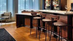 A bar area with a long counter, three stools, and a wine glass. - Courtyard® by Marriott® Fort Lauderdale City of Plantation (Plantation)