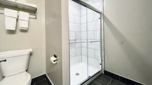 Ein modernes Badezimmer mit Toilette, einer Duschkabine aus Glas und einem Handtuchhalter mit gefalteten Handtüchern.