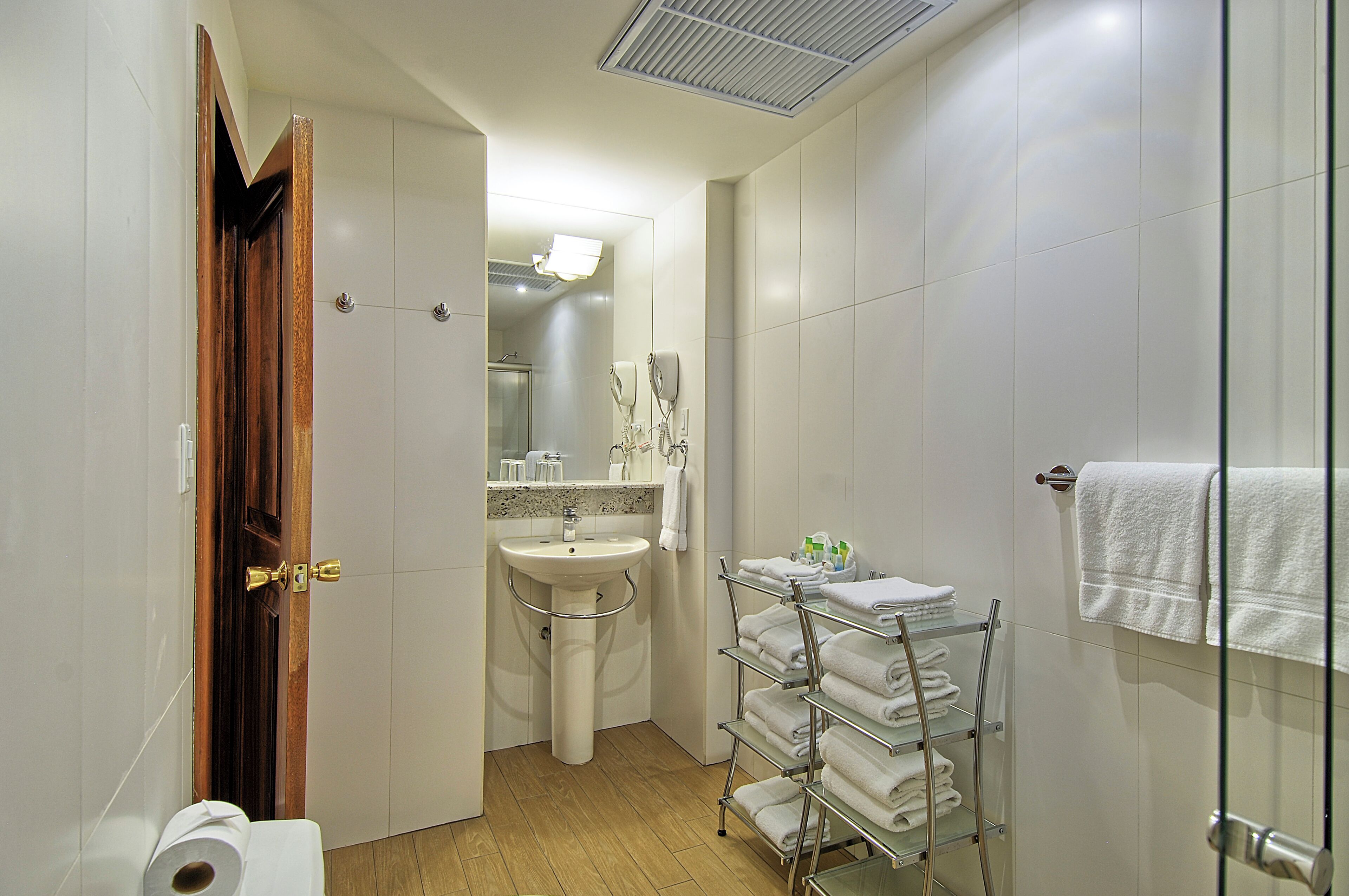 A bathroom with a sink, mirror, towel rack, and toilet.