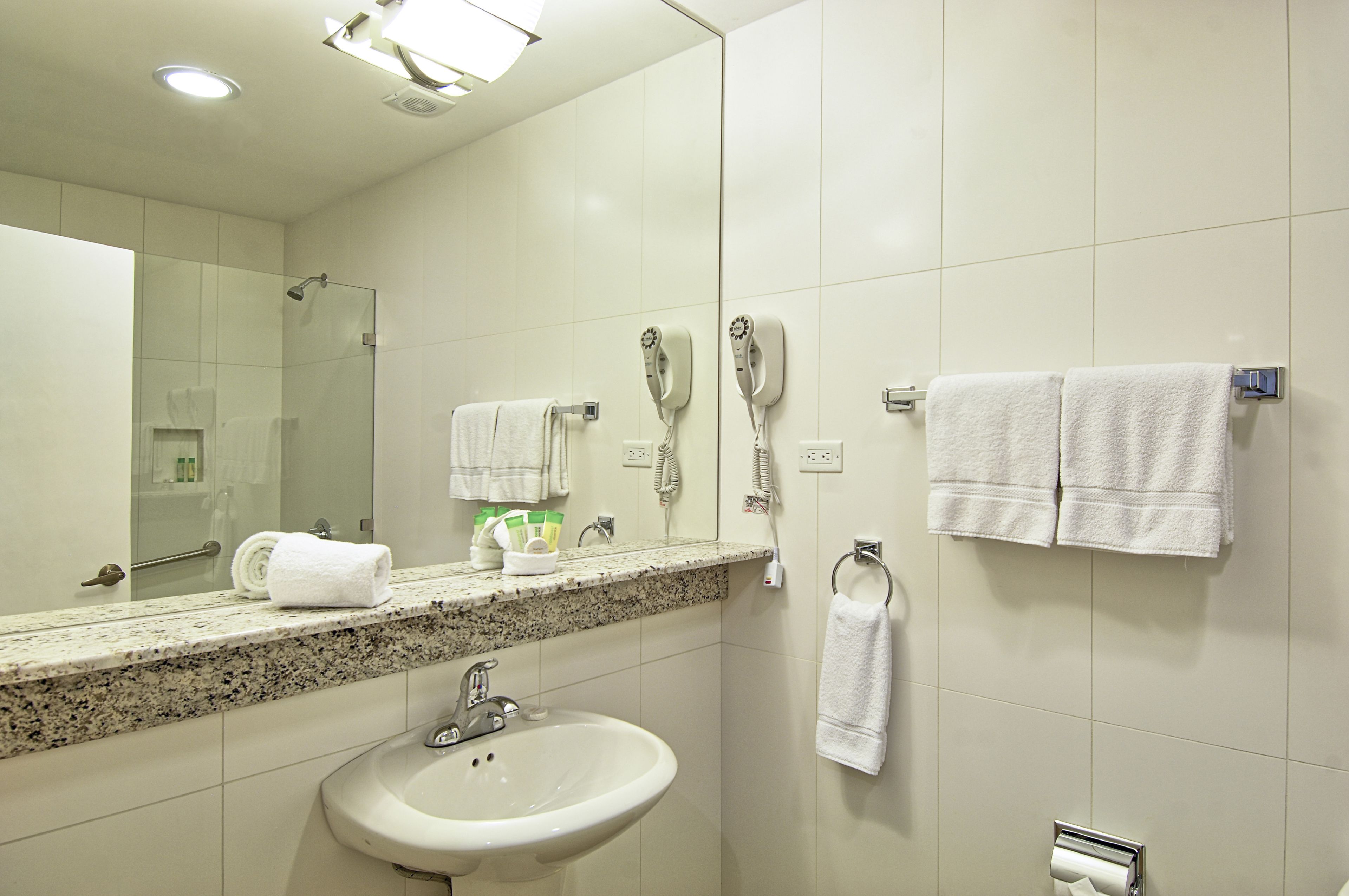 A bathroom with a sink, mirror, towel rack, and hairdryer.