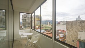 A balcony with white chairs and a small table, overlooking a cityscape with buildings and mountains. - Balmoral Hotel San José CR, Historic District (San José)