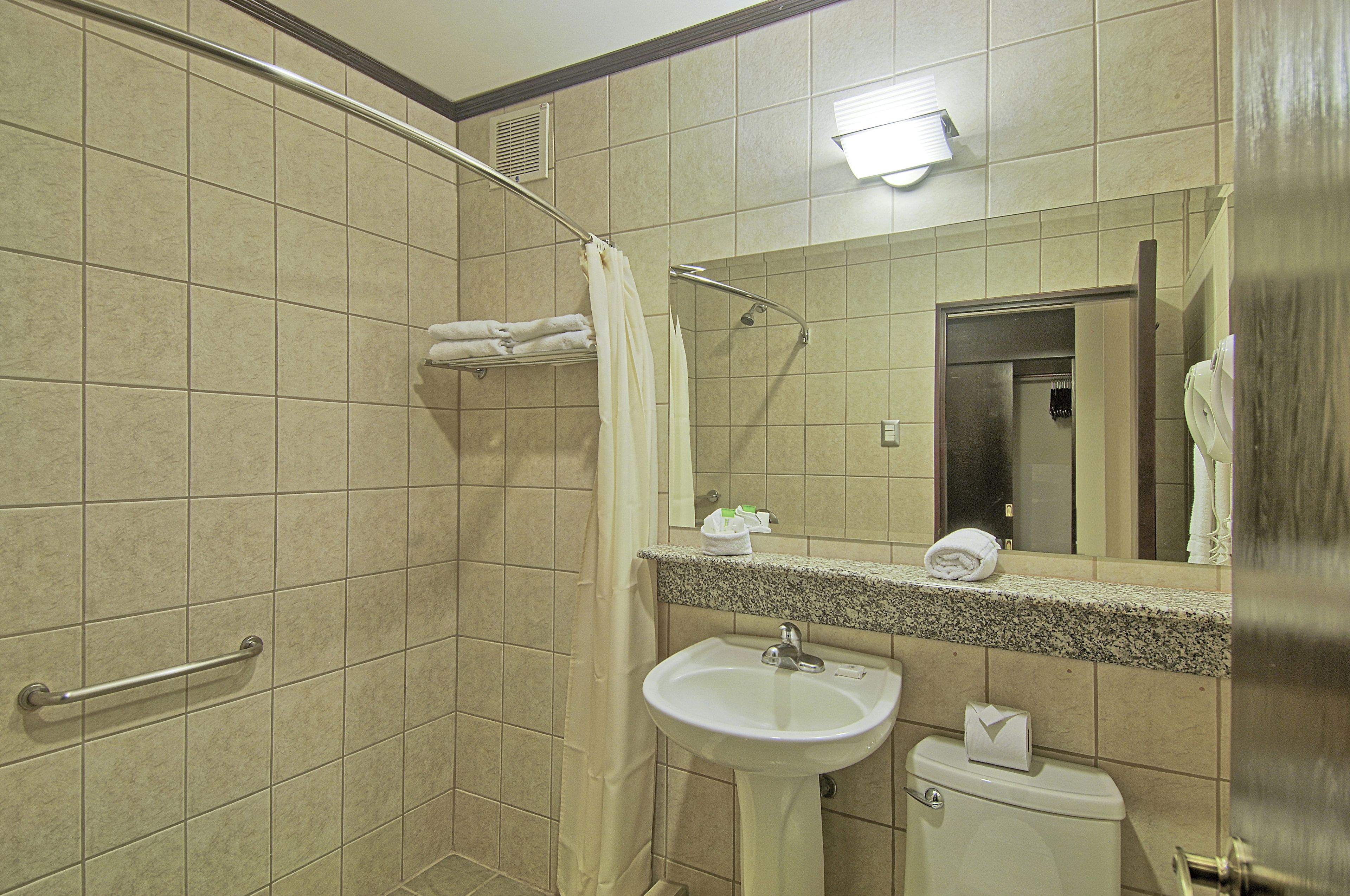 A bathroom with a shower, sink, and toilet.