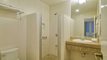 A bathroom with a shower, toilet, sink, and a towel rack.