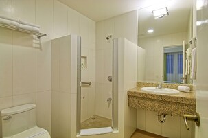 A bathroom with a shower, toilet, sink, and a towel rack.