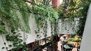 A staircase with a wooden handrail and steps, surrounded by lush greenery and a dining area with tables and chairs. - Balmoral Hotel San José CR, Historic District (San José)