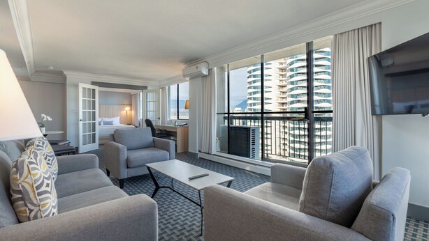 Habitación de hotel moderna con balcón, escritorio y televisor.