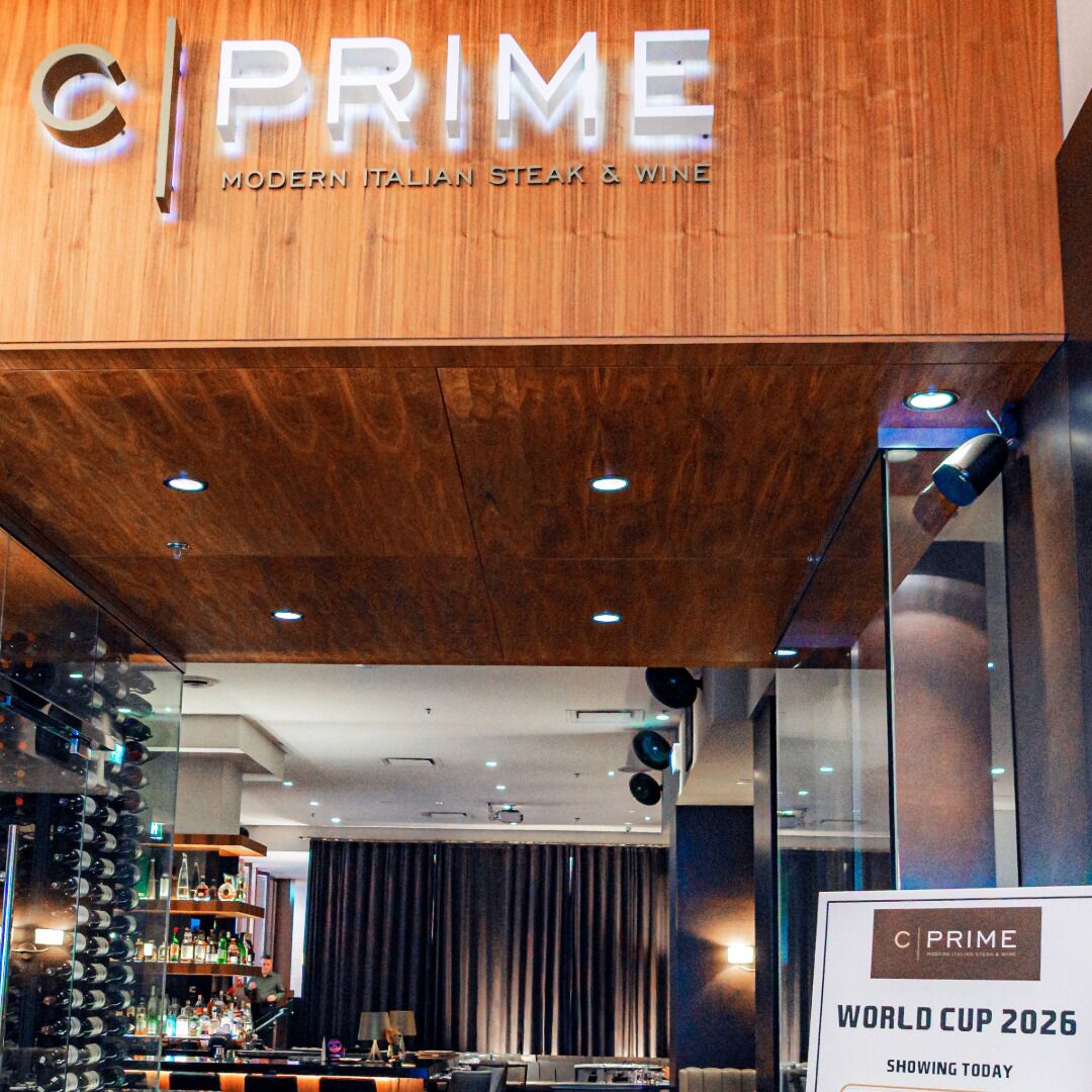 A restaurant interior with a wooden ceiling, a bar area with wine bottles, and a sign for the World Cup 2026.