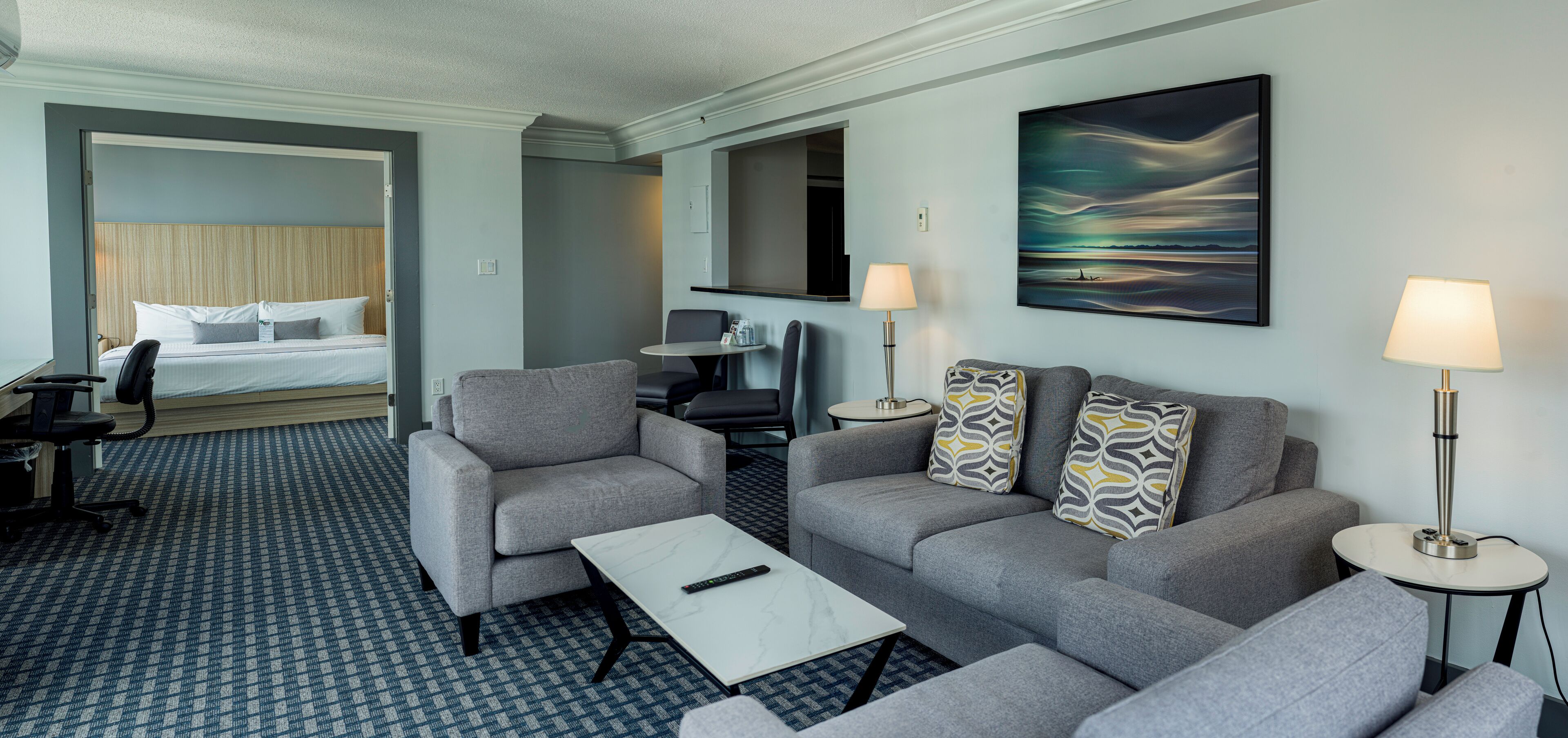 Habitación de hotel con cama, escritorio, sofá, mesa de centro y dos lámparas.