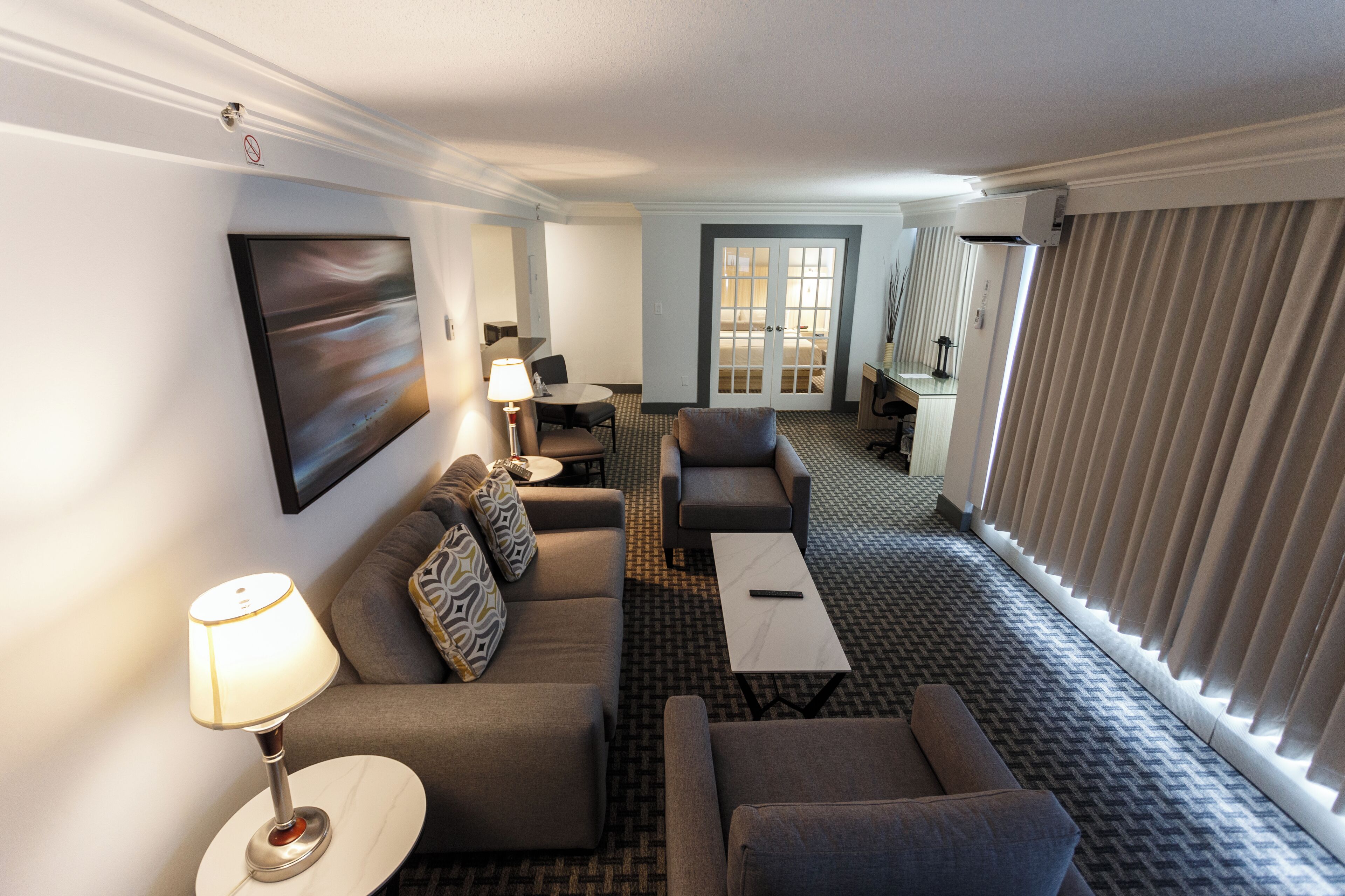 Une chambre d’hôtel avec un canap é, un fauteuil, une table basse et un tableau au mur.