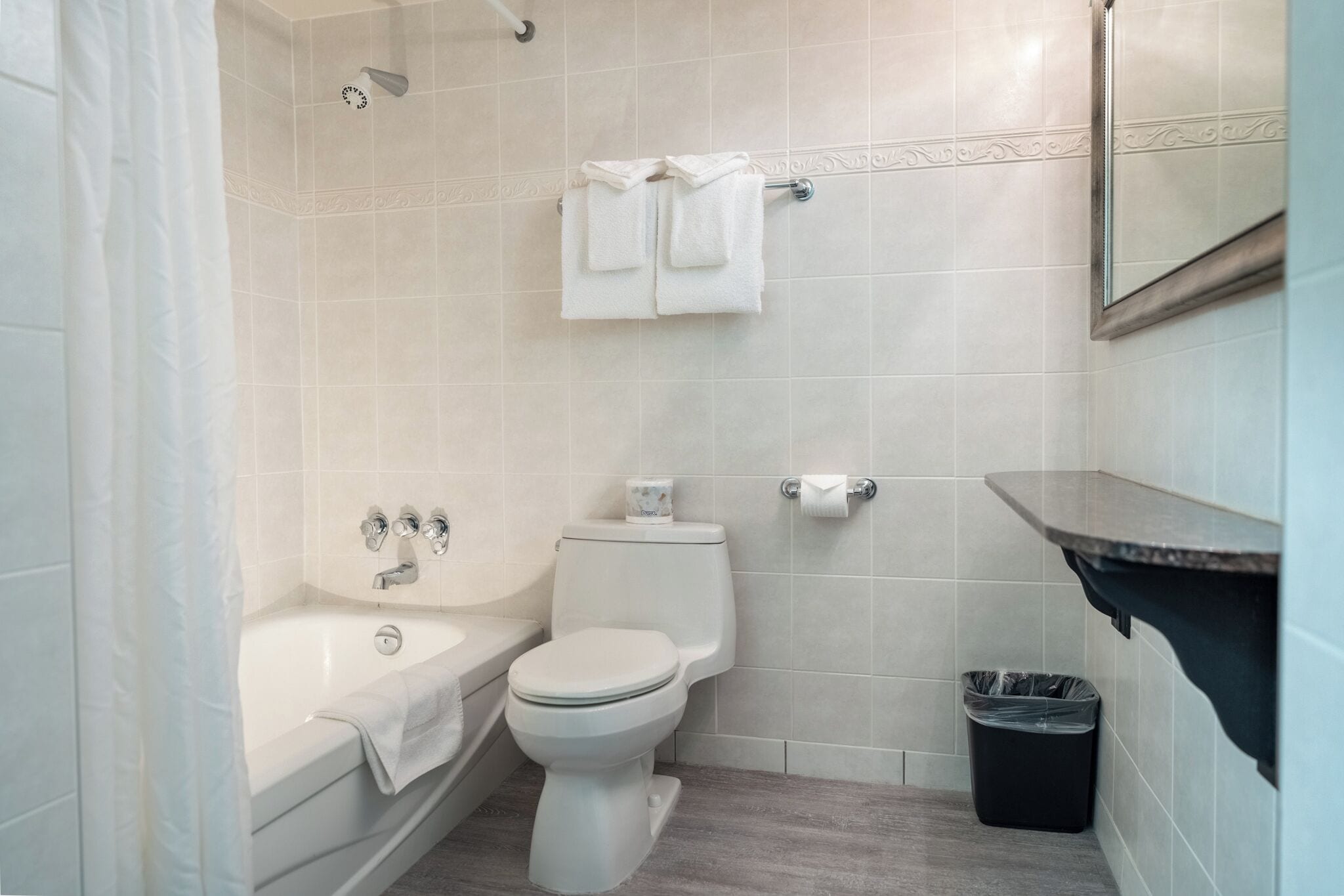A bathroom with a bathtub, toilet, and a towel rack with towels.