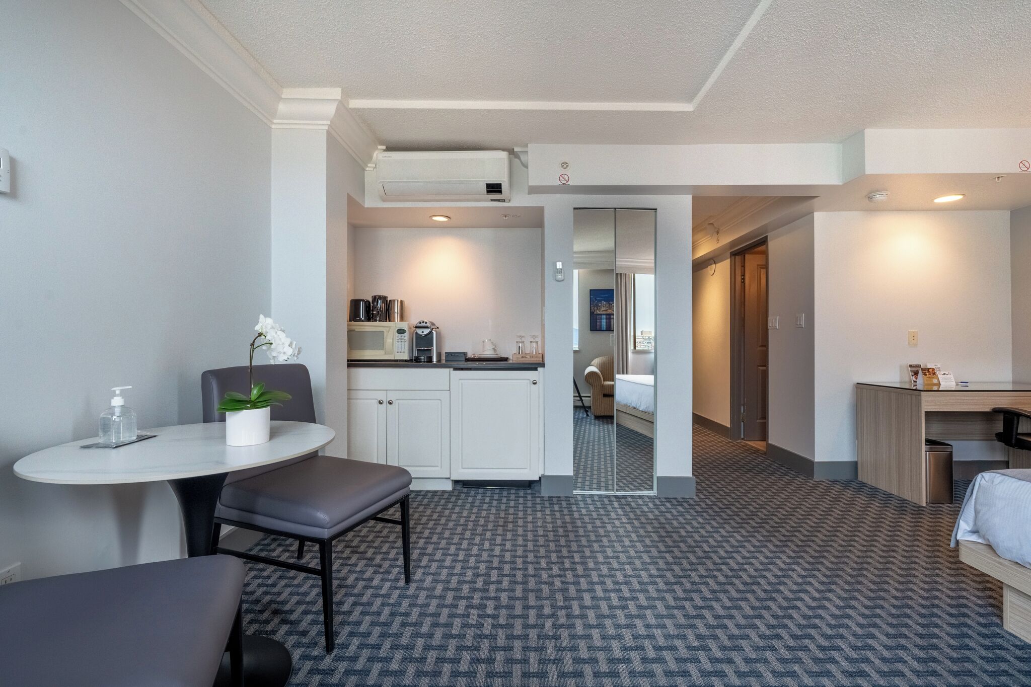 Ein kleines Hotelzimmer mit Kochnische, Essecke und Bett.